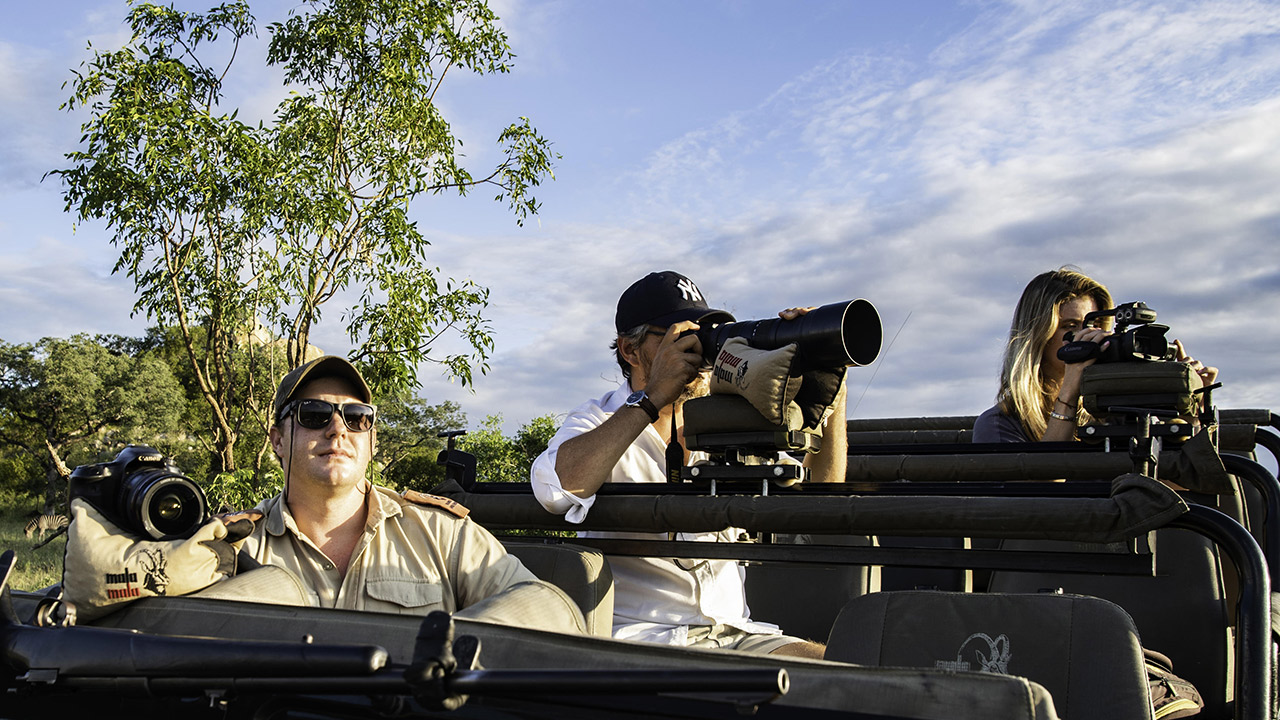 Taking wildlife photos in a game vehicle in Mala-Mala game reserve while traveling on a luxury safari package.