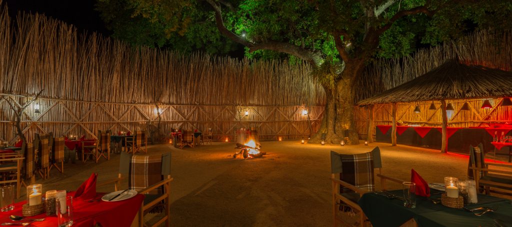 copy_of_mala_mala_main_camp-3 Fine dining setting outside with fire at luxury accommodation part of luxury safari tour at mala mala reserve with Premier Africa.